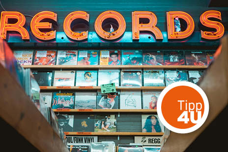 Schallplattenregal mit leuchtendem ‚Records‘‑Schild und Tipp‑4U‑Kreis.