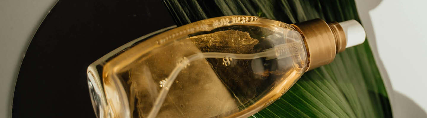 Duftflakon liegt auf grünem Blatt