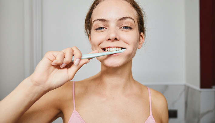 Frau hat Zahnbürste im Mund