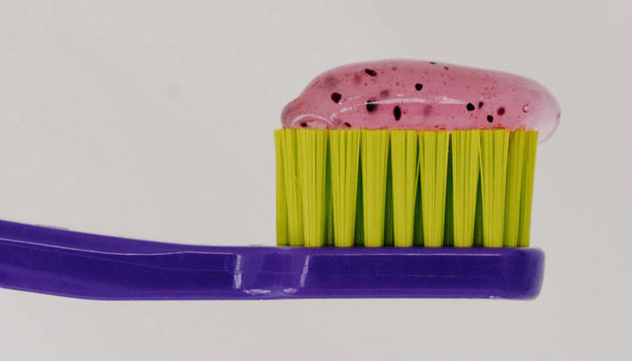 Lila Zahnbürste mit bunter Zahnpasta drauf