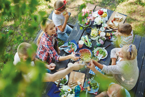 Familie sitzt draußen an einem Tisch