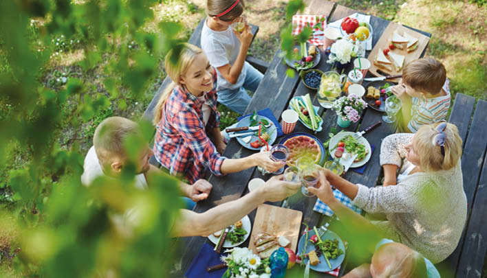 Familie sitzt draußen am Tisch zusammen