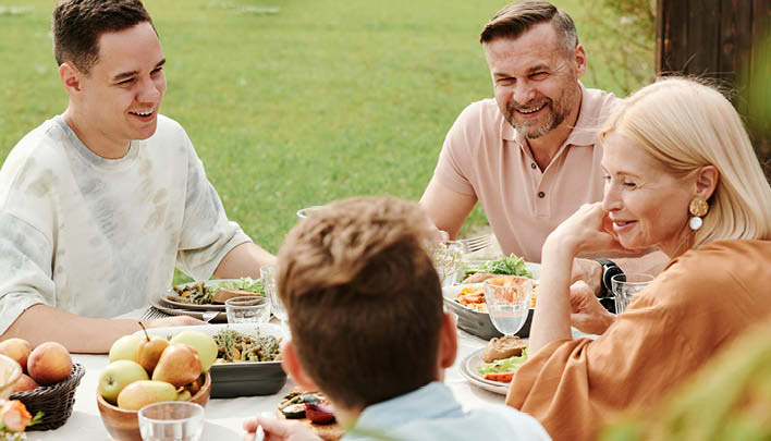 Familie sitzt draußen und isst