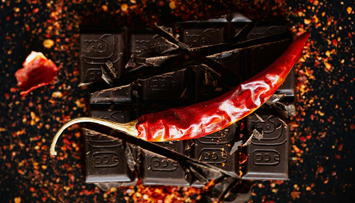 Zartbitterschokoladenbruch Chilipulver Schote dunkler Hintergrund