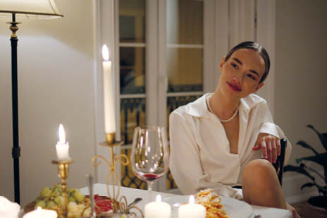 Frau mit braunen Haaren sitzt an einem Tisch mit Kerzen