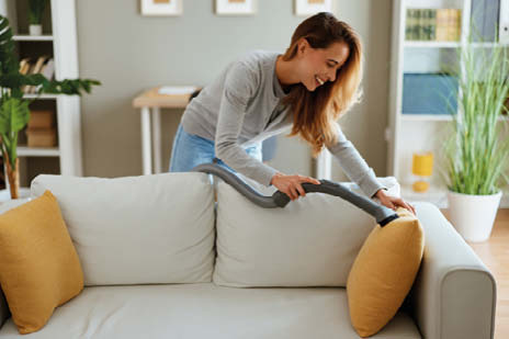 Frau saugt das Sofa ab