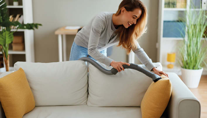Frau saugt das Sofa ab