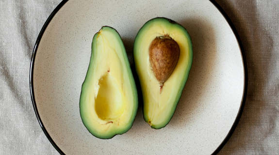 lifestyle-flatlay-teller-halbierte-avocado-beige-tischdecke-04-24-96382-0