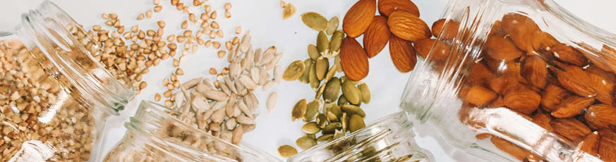 lifestyle-header-flatlay-vier-glaeser-mit-hanfsamen-sonnenlumenkernen-kuerbiskernen-mandeln-weisser-hintergrund-04-24-96378-0