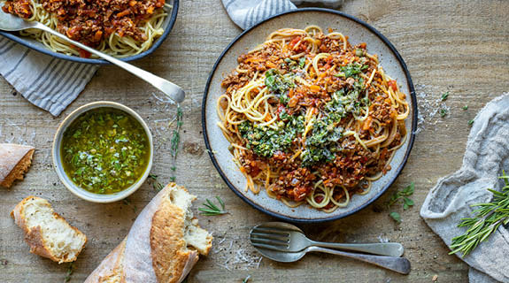 lifestyle-tofu-bolognese-nudeln-pesto-teller-holzhintergrund-besteck-01-25-104499-0