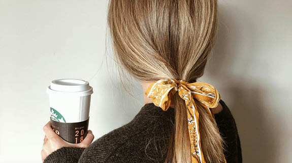 lifestyle-aufm-frau-ru-eckenansicht-blondes-haar-gelbe-schleife-kaffeebecher-575x320-98692-0