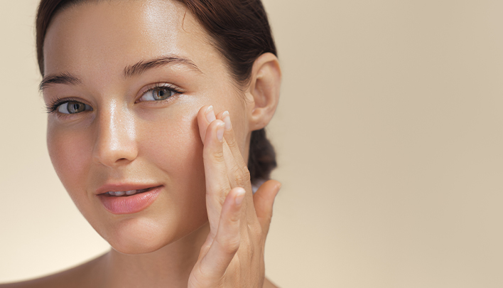 Eine dunkelhaarige Frau in Nahaufnahme cremt sich das Gesicht ein