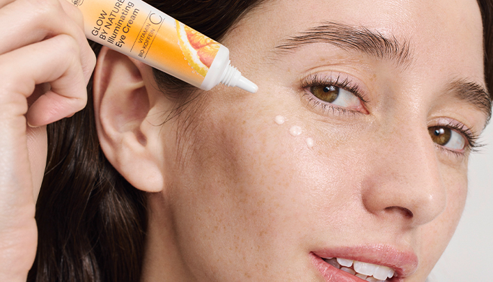 Eine dunkelhaarige Frau in Nahaufnahme trägt Augencreme auf