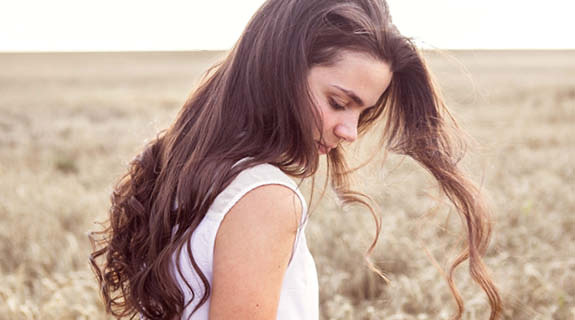 lifestyle-junge-frau-weizenfeld-langes-welliges-braunes-haar-weisses-top-575x320-90675-0