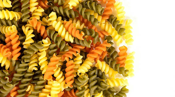 lifestyle-gru-ene-orange-gelbe-fusilli-wei-er-hintergrund-575x320-98707-0