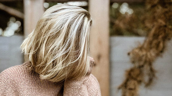 lifestyle-frau-verdecktes-gesicht-blonder-longbob-beiger-pullover-im-freien-575x320-98687-0