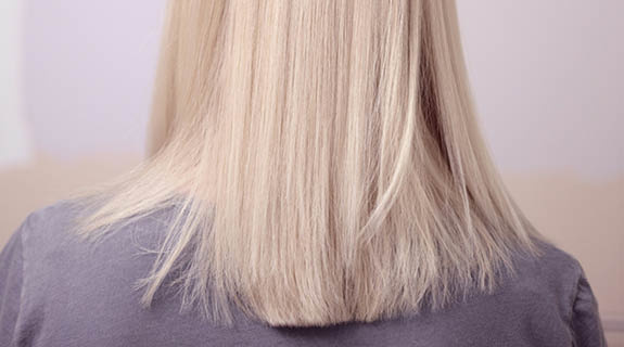 lifestyle-ru-eckenansicht-frau-blondes-haar-graues-oberteil-lila-rosa-hintergrund-575x320-98690-0