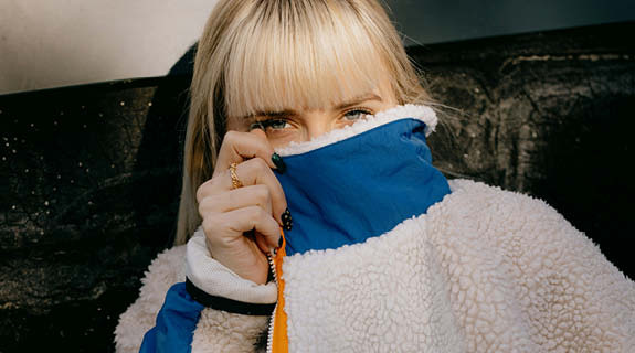 lifestyle-junges-maedchen-blond-pony-gesicht-hinter-jacke-versteckt-01-25-104263-0