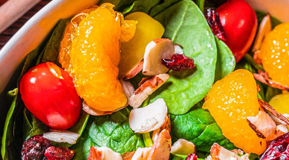 lifestyle-grossaufnahme-salatteller-mit-gruenem-blattsalat-datteltomaten-mandarinenscheiben-cranberries-nuessen-575x320-92074-0
