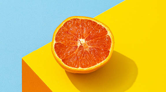 lifestyle-halbe-orange-gelber-sockel-hellblauer-hintergrund-04-24-96431-0