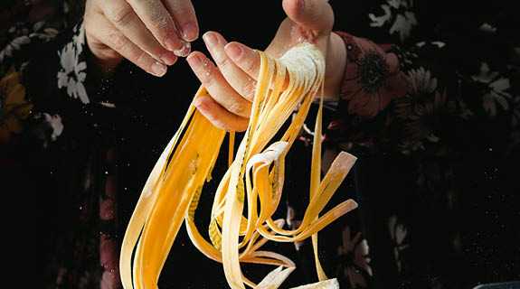 lifestyle-aufm-ha-ende-selbstgemachte-pasta-mehl-geblu-emtes-hemd-dunkler-hintergrund-575x320-98708-0