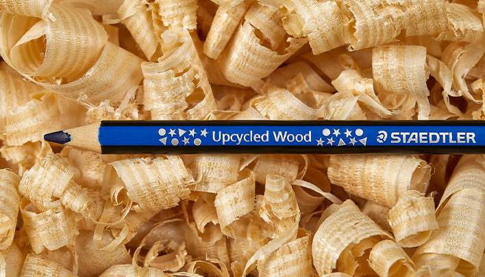 Ein angespitzter blauer Buntstift mit der Aufschrift "Upcycled Wood" von Staedtler auf Holzspäne