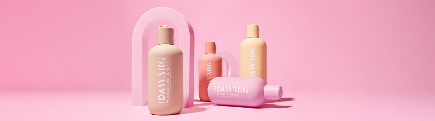 Ida‑Warg‑Haarpflegeprodukte in Pastellfarben vor rosa Hintergrund arrangiert