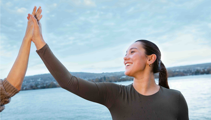 Zwei Personen geben sich ein High‑Five vor einem See