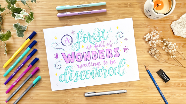 Handlettering mit Buntstiften auf Holztisch