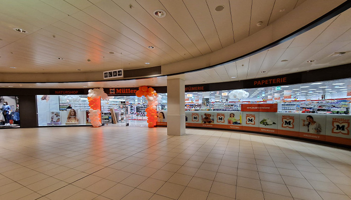 Eingang eines Müller-Markts mit orange-weißen Luftballonbögen